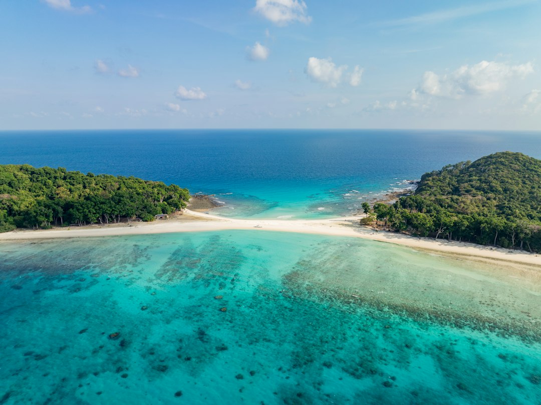 Aerial view of tropical islands connected by a white sandbar. Photo by Nabil Naidu on Unsplash.