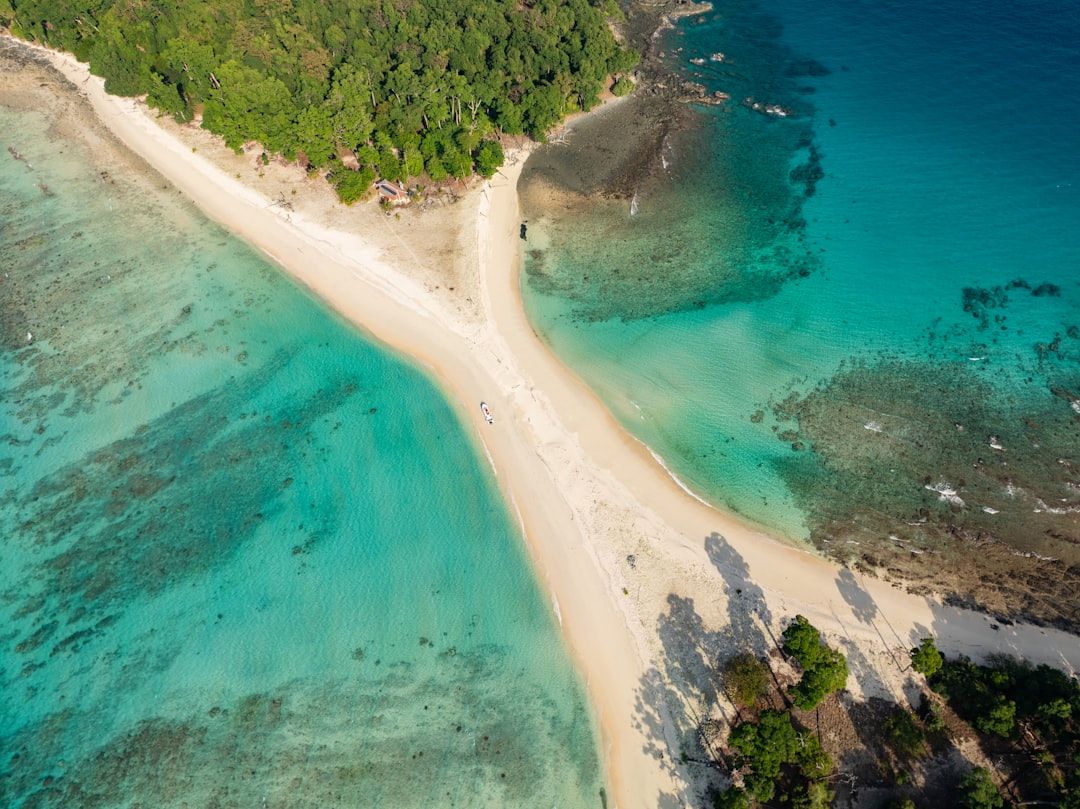 Aerial view of a sandbar dividing turquoise tropical water. Photo by Nabil Naidu on Unsplash.