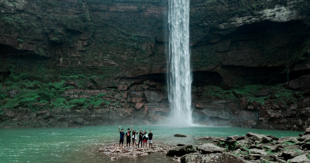 Travellers near a Meghalaya waterfall. Photo by Hadwt on Unsplash.